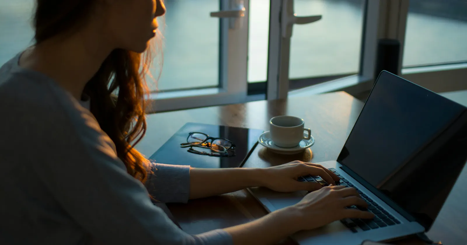 A freelancer working on a laptop at a desk by the window