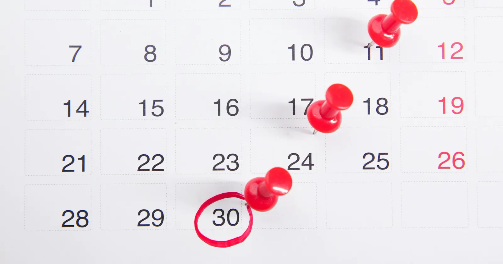 A wall calendar with red pins and a due date circled in red